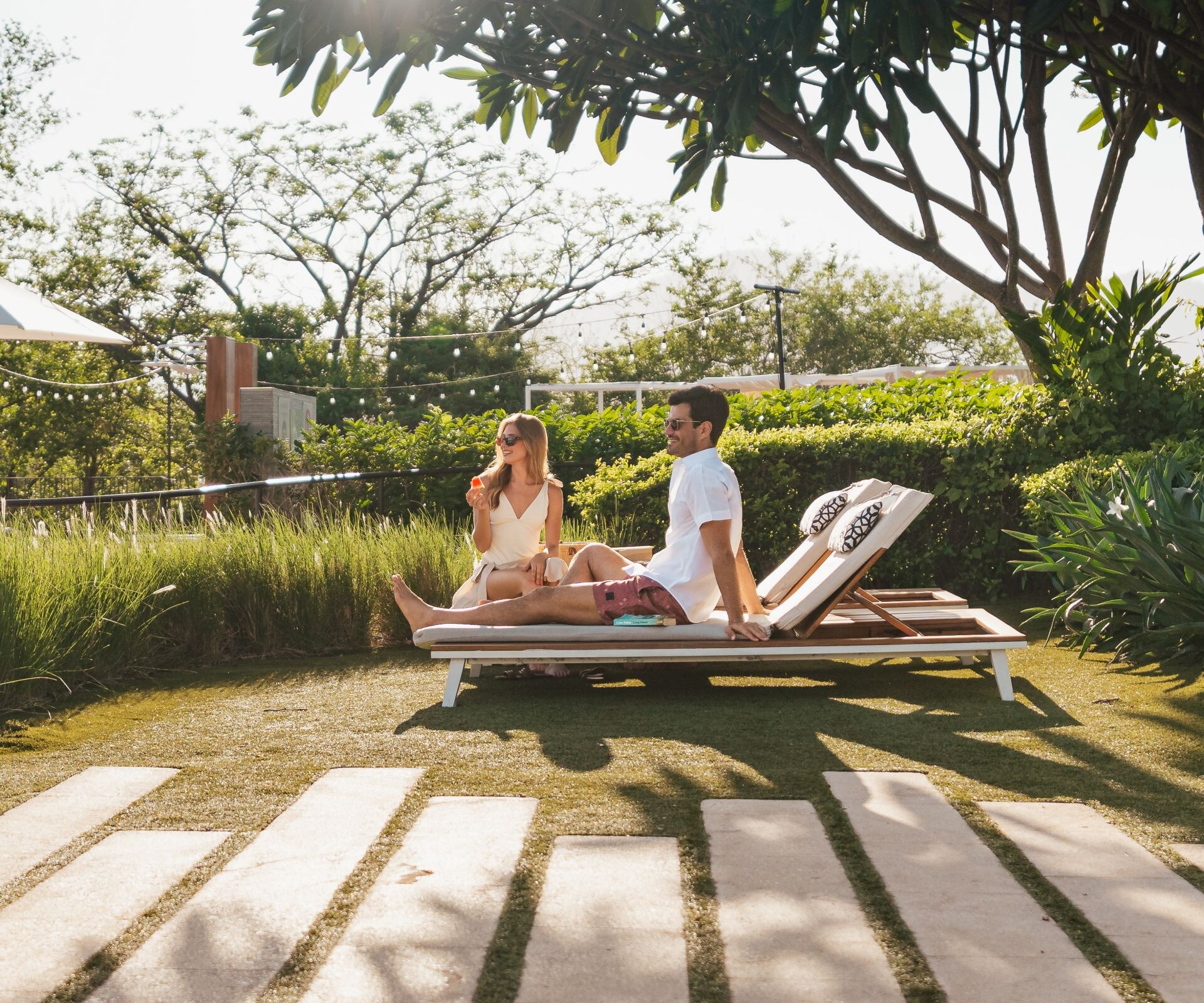 Couple laying in a wooden bed by the pool