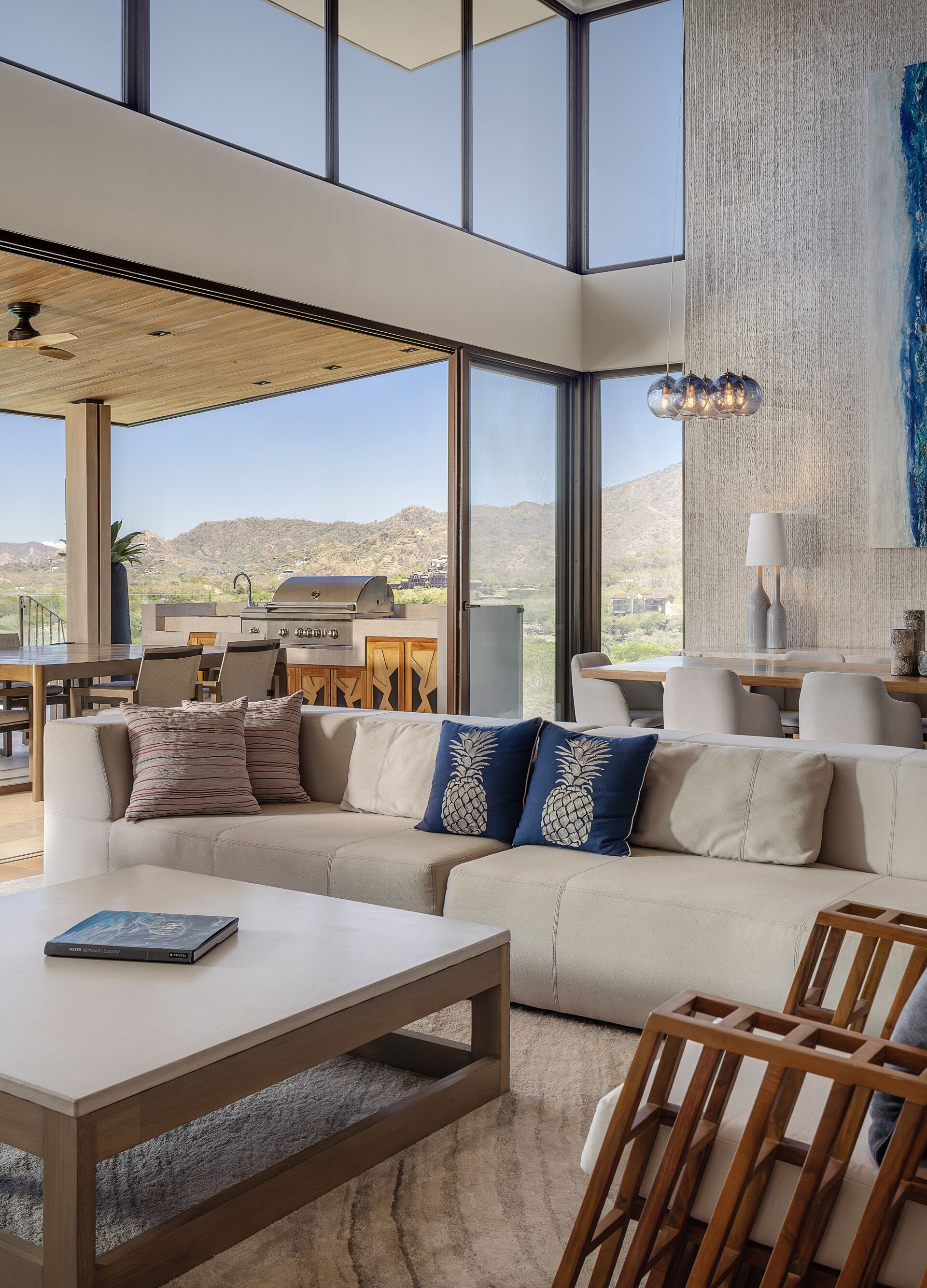 Televisor, sofá y mesa de comedor con vista al mar