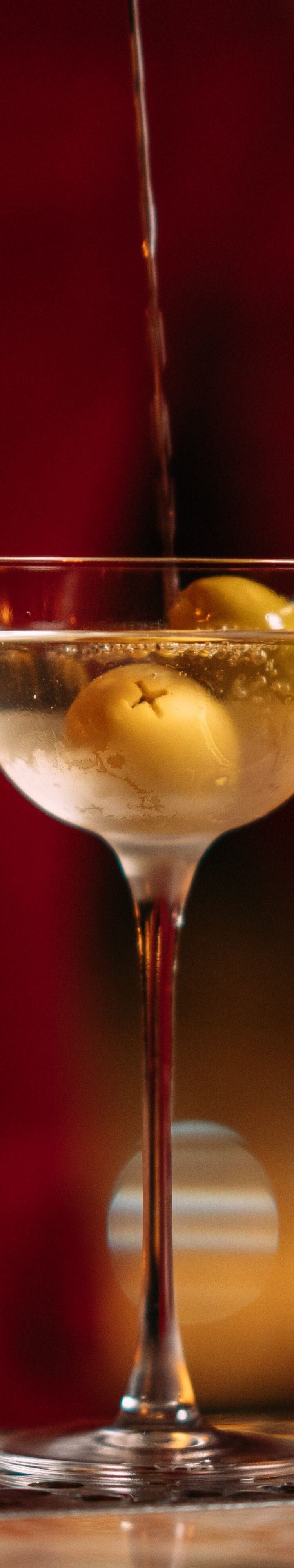 Martini with olive garnish being prepared