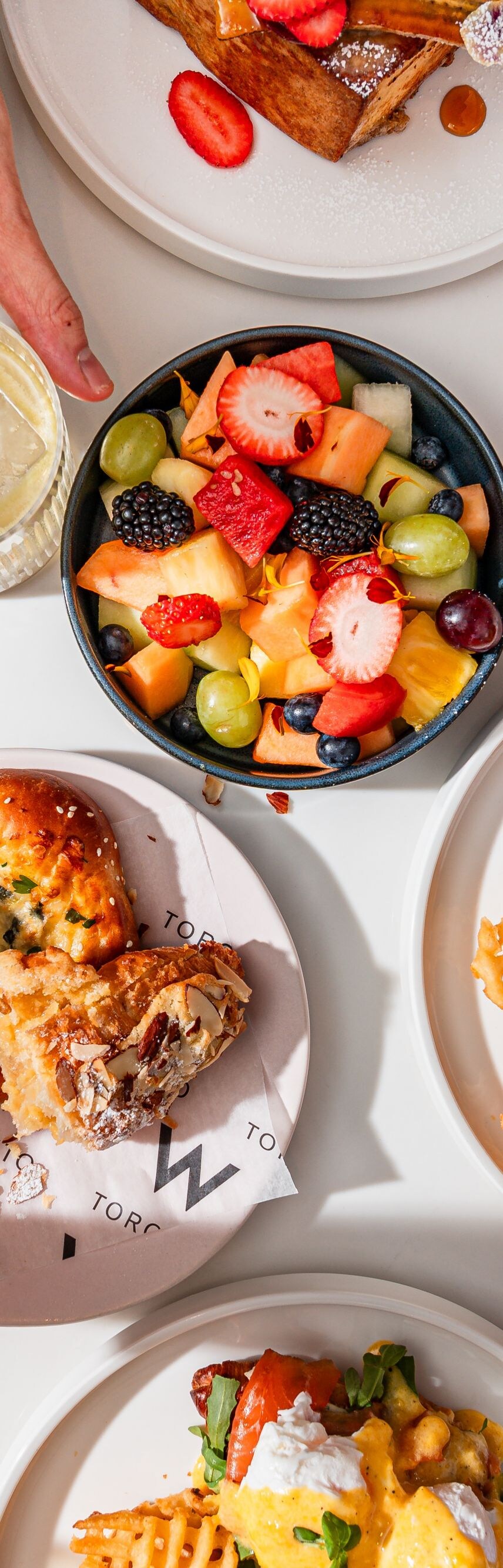 Overhead plates with eggs, pastries, fruit