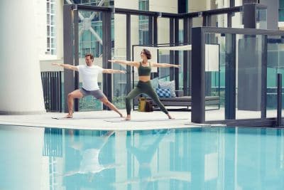 Two people doing yoga poolside