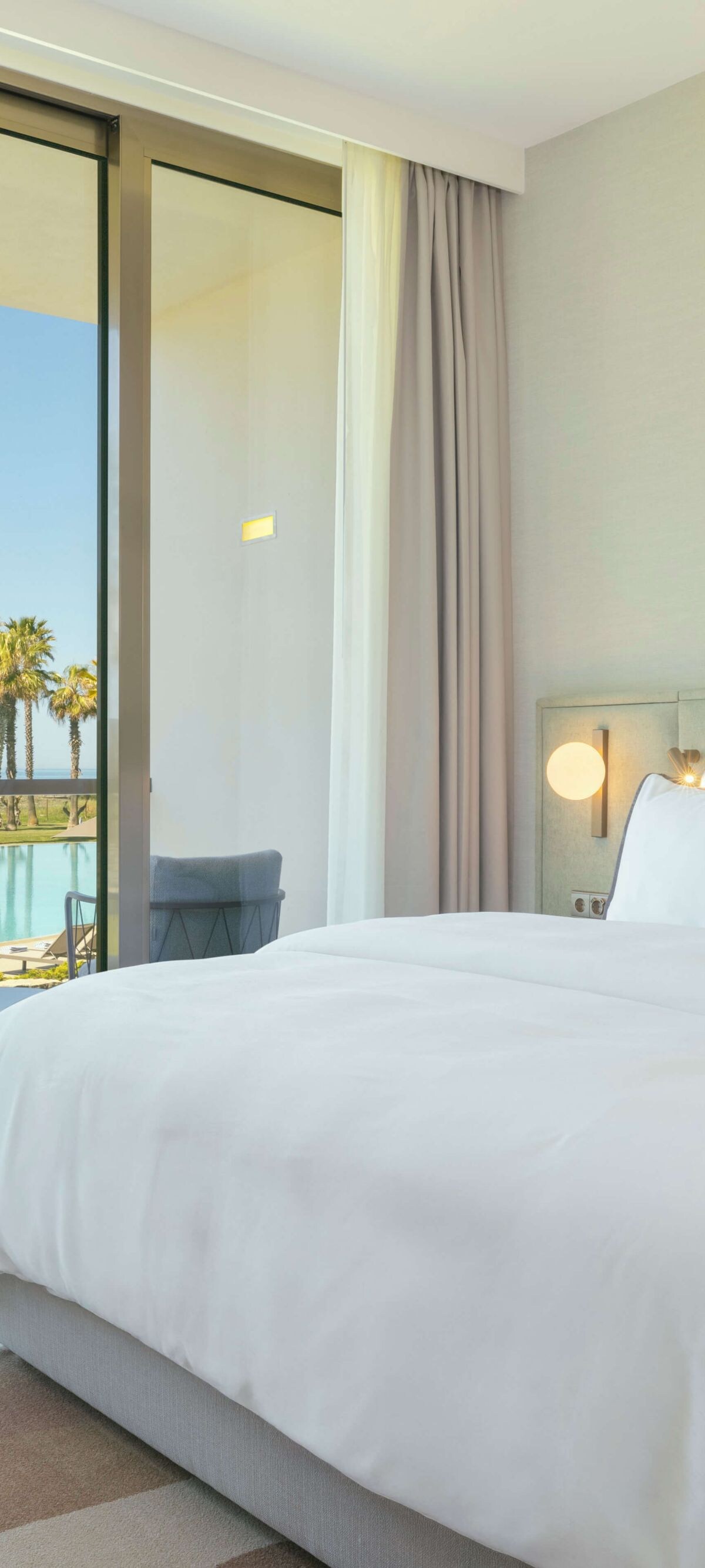 Hotel bedroom with pool view and private balcony