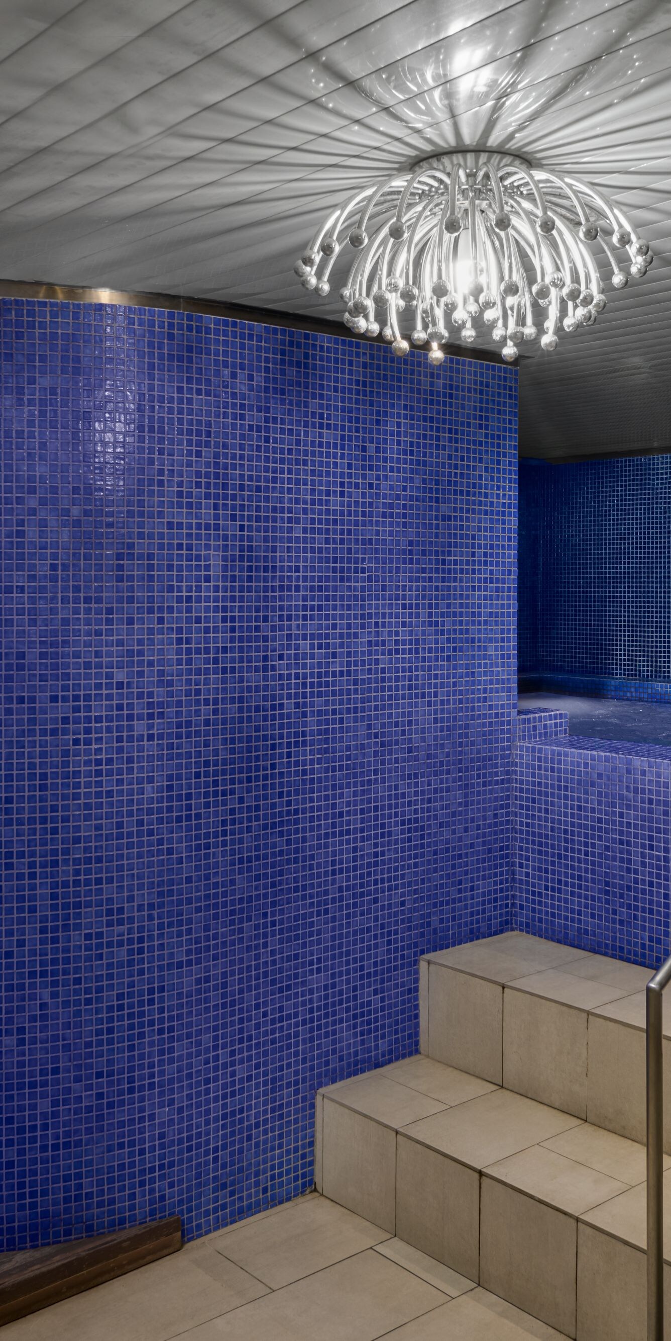 Indoor pool with blue tiles and chandelier