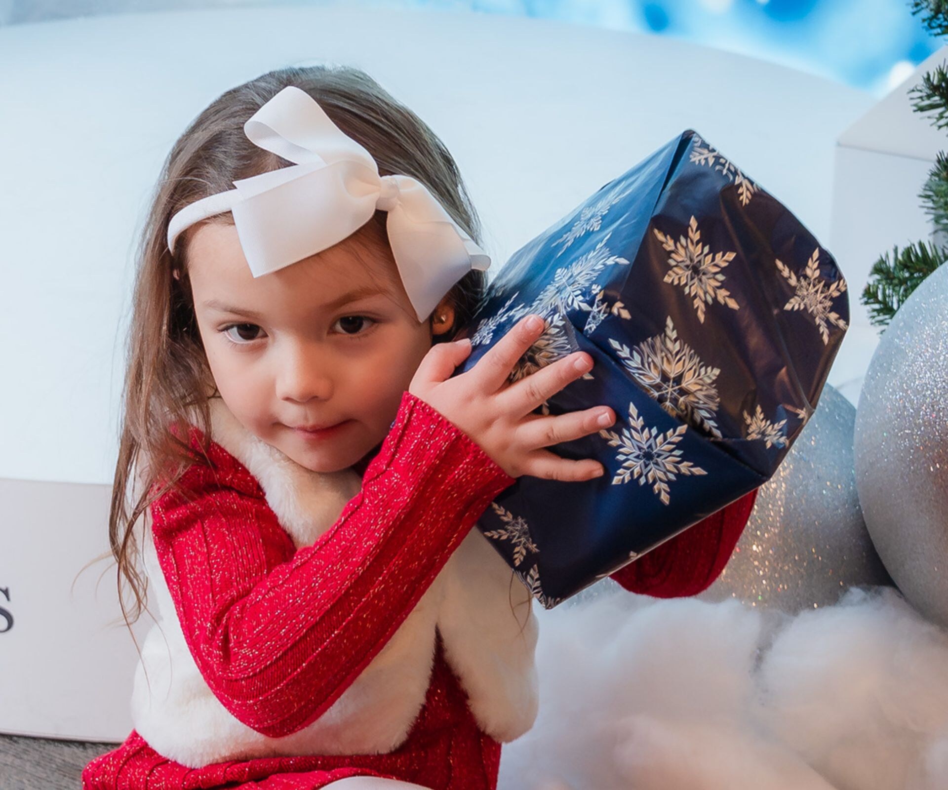 Enfant posant avec des cadeaux lors d'une exposition de Noël