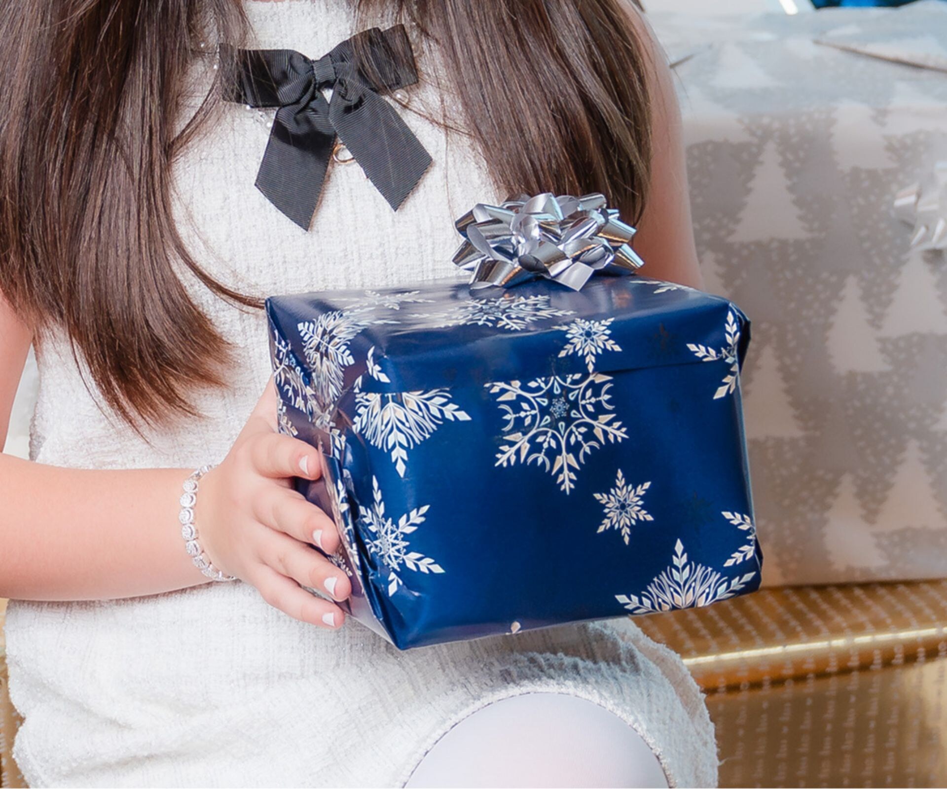 Enfant tenant un cadeau près d'un sapin décoré