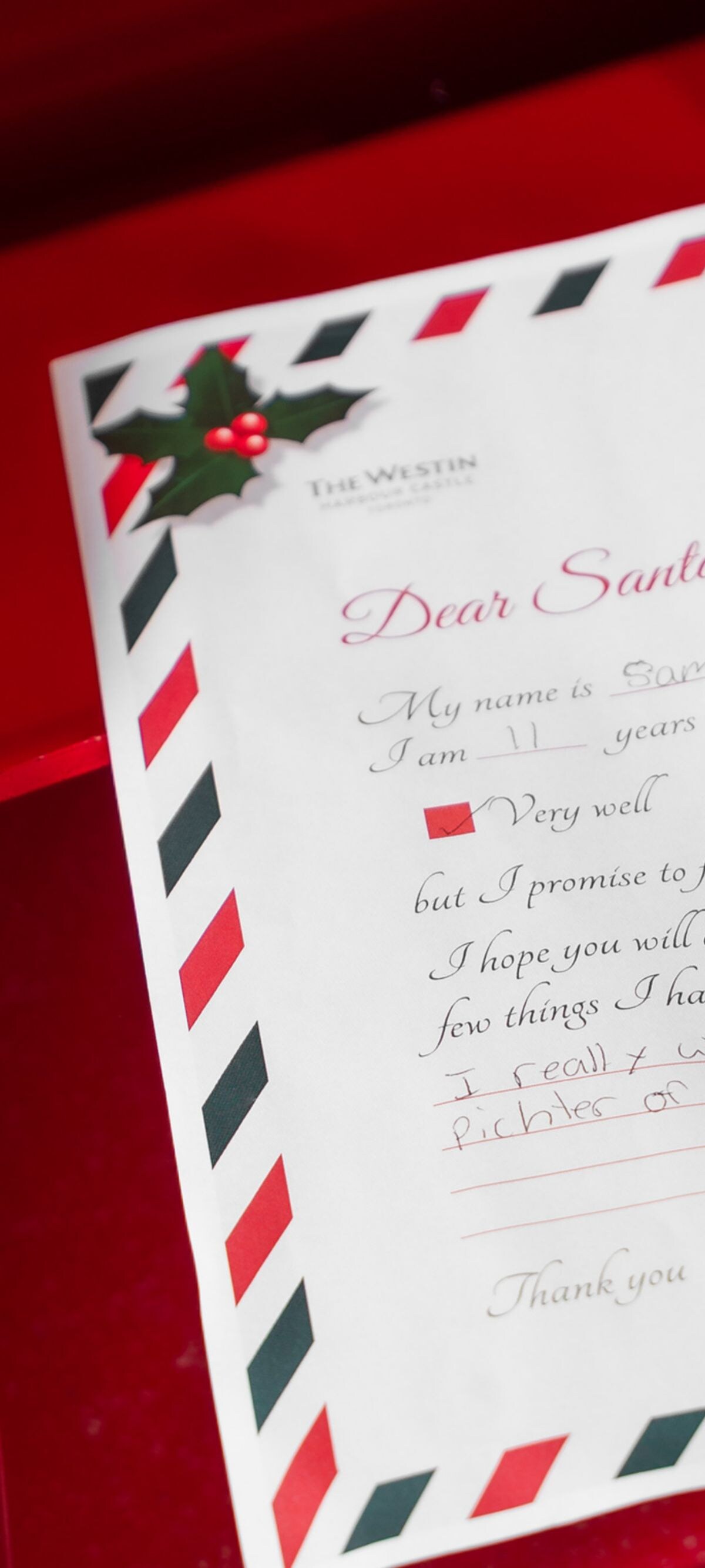 Un enfant place une lettre dans la boîte aux lettres du Père Noël.