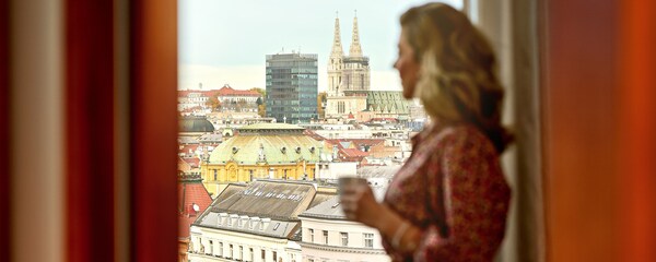 Eine Frau blickt durch ein Fenster auf Zagreb