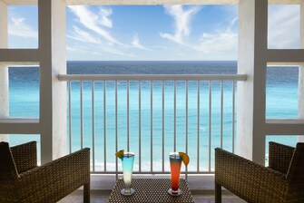 Balcón, sillas, bebidas y vista al mar