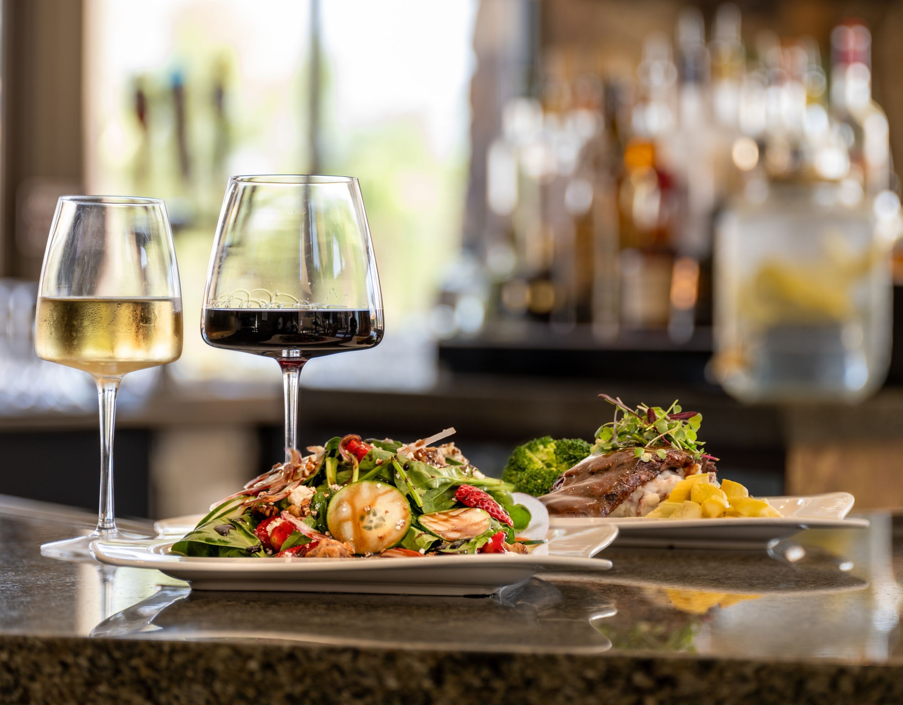 Wine, shrimp salad, and steak on dining table