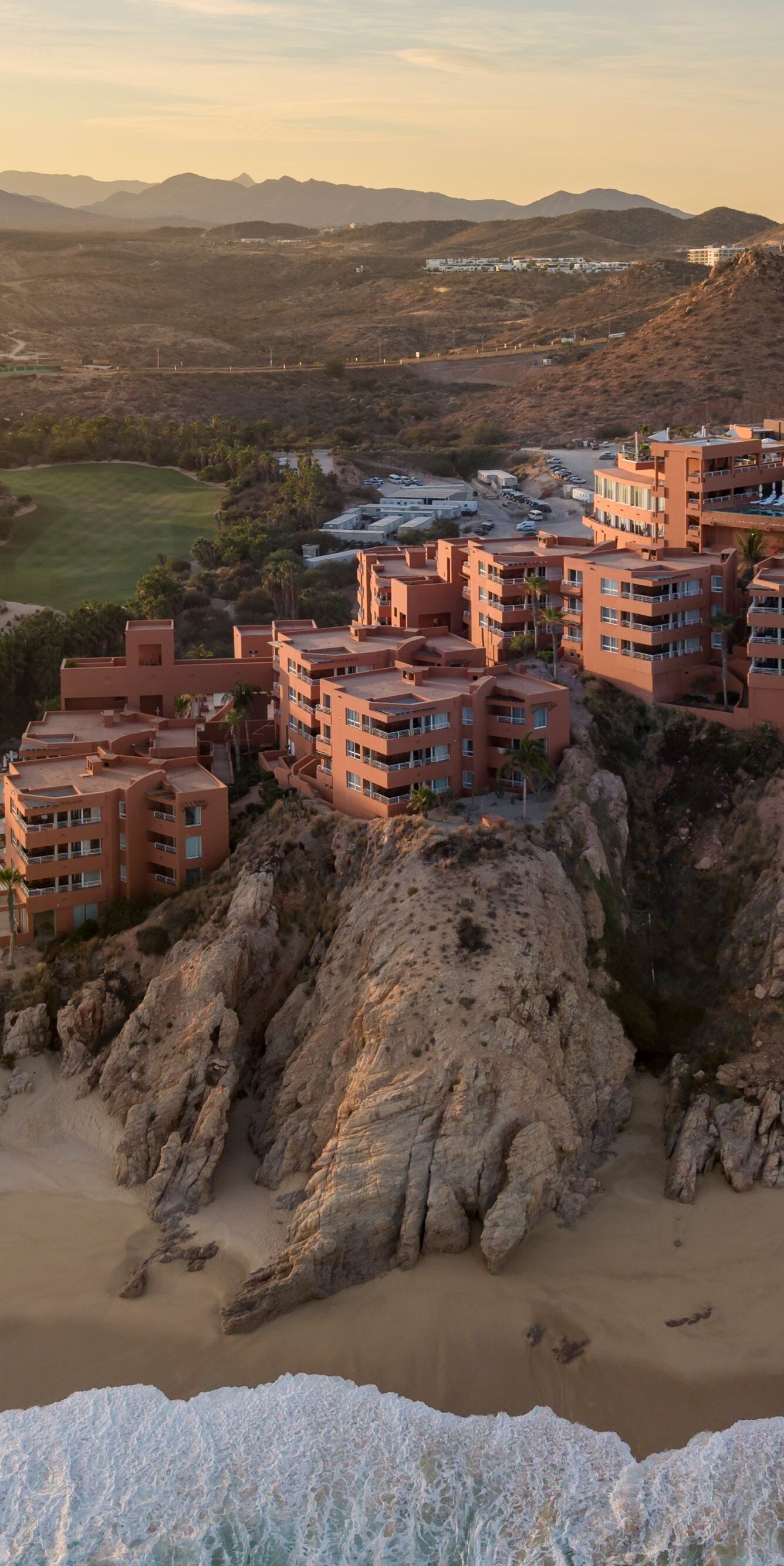 Clifftop resort above sandy beach and ocean waves