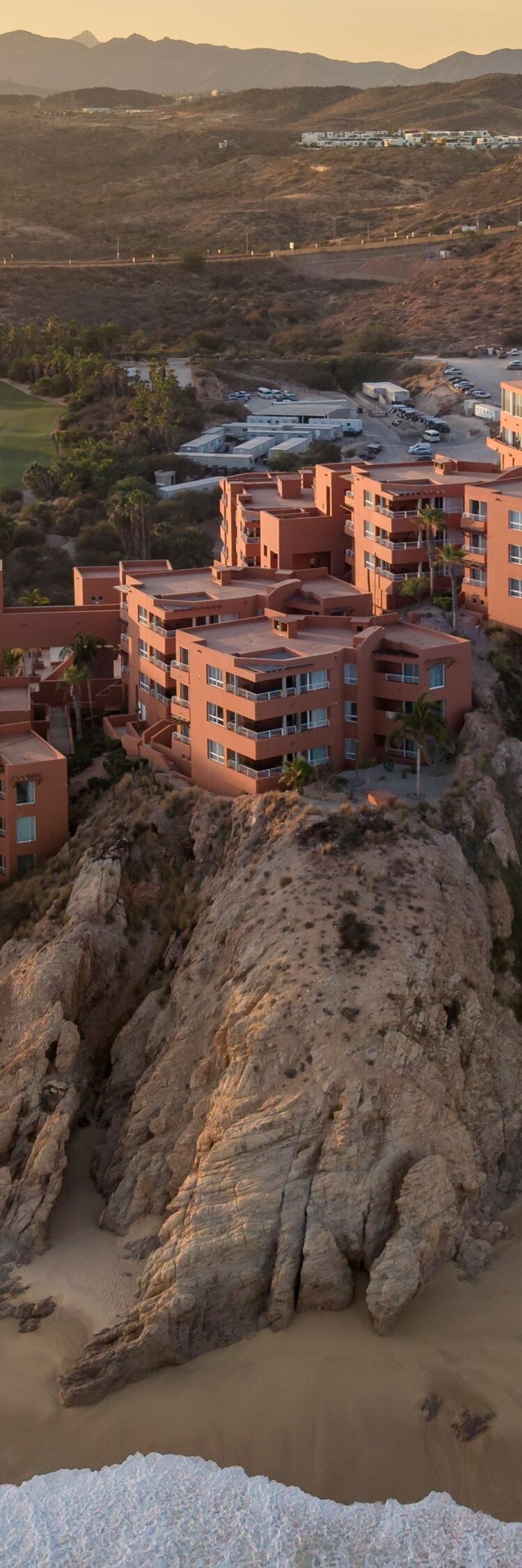 Clifftop resort above sandy beach and ocean waves
