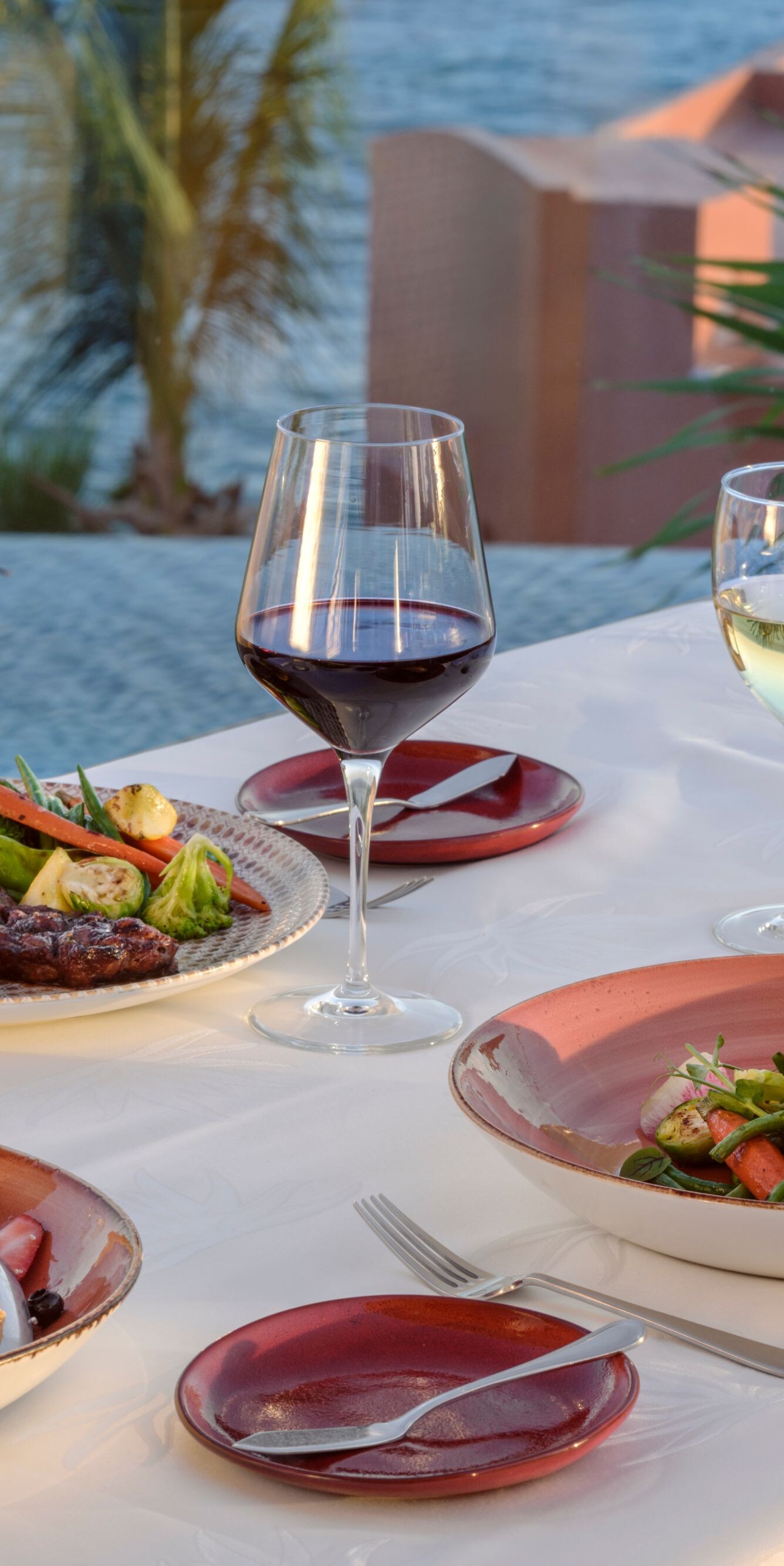 Oceanfront dining table with plated meals and wine