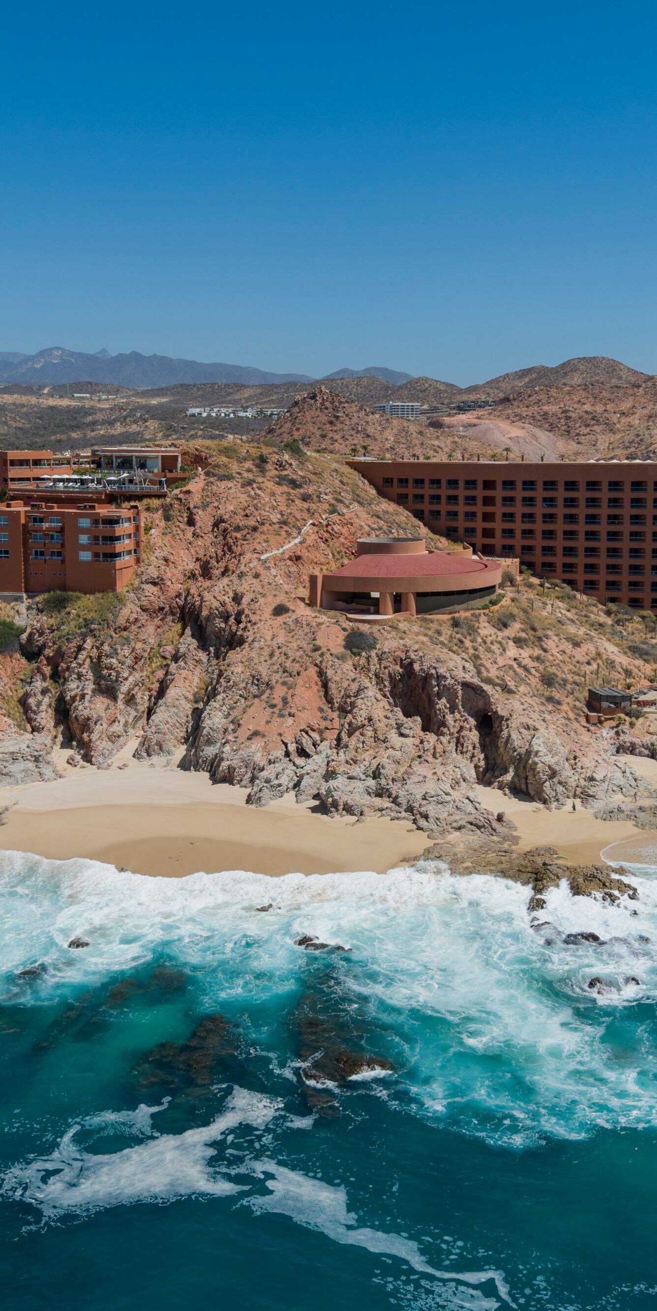 Aerial view of beachfront resort with rocky cliffs