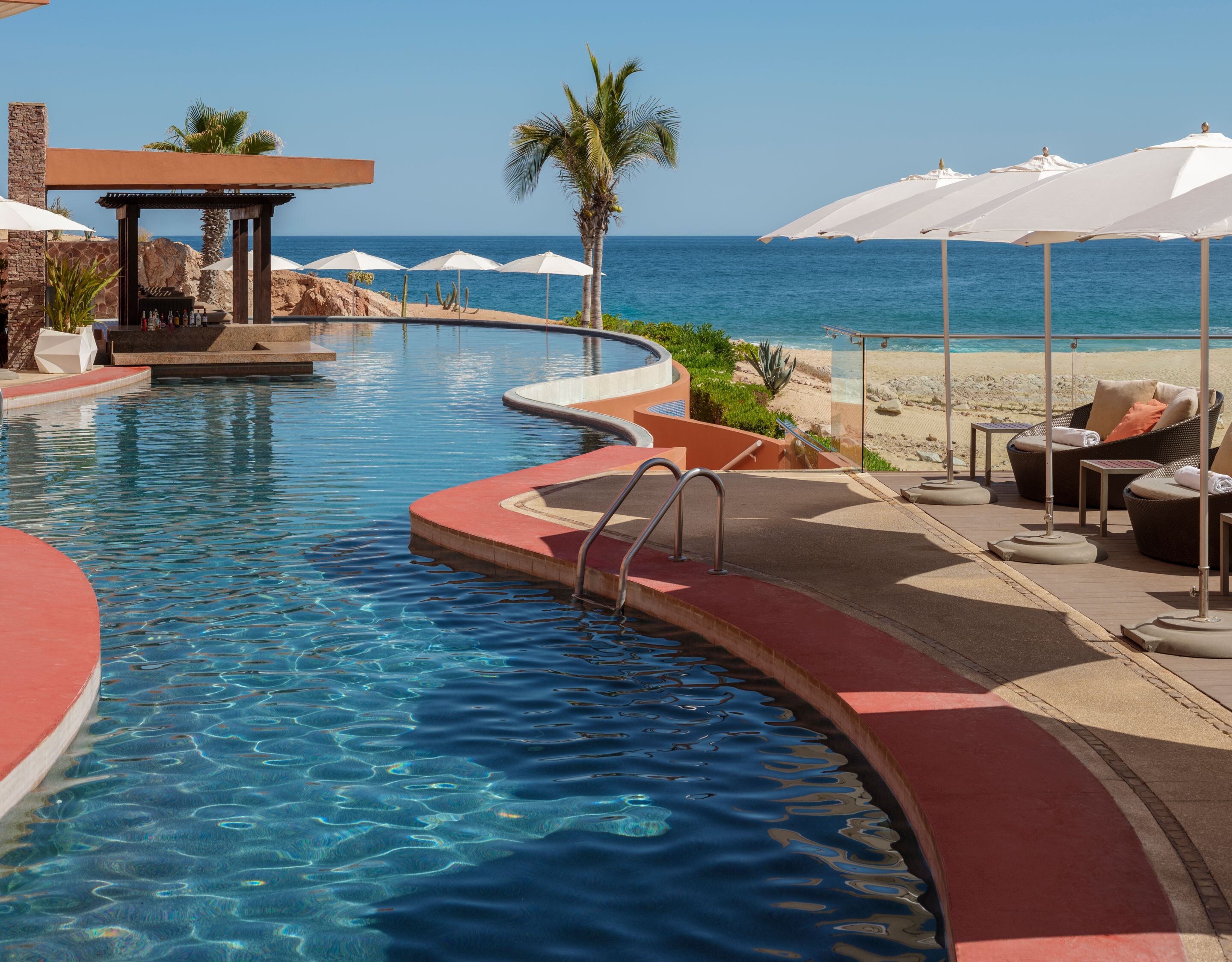 Curved beachfront pool with umbrellas and ocean 