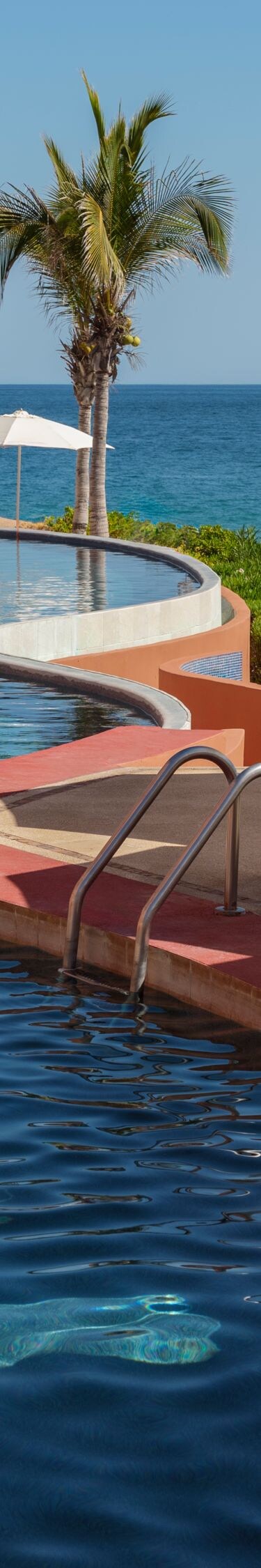 Curved beachfront pool with umbrellas and ocean 