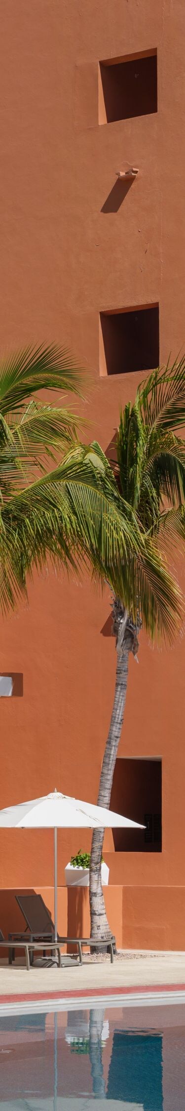 Pool beside resort building with palm trees 