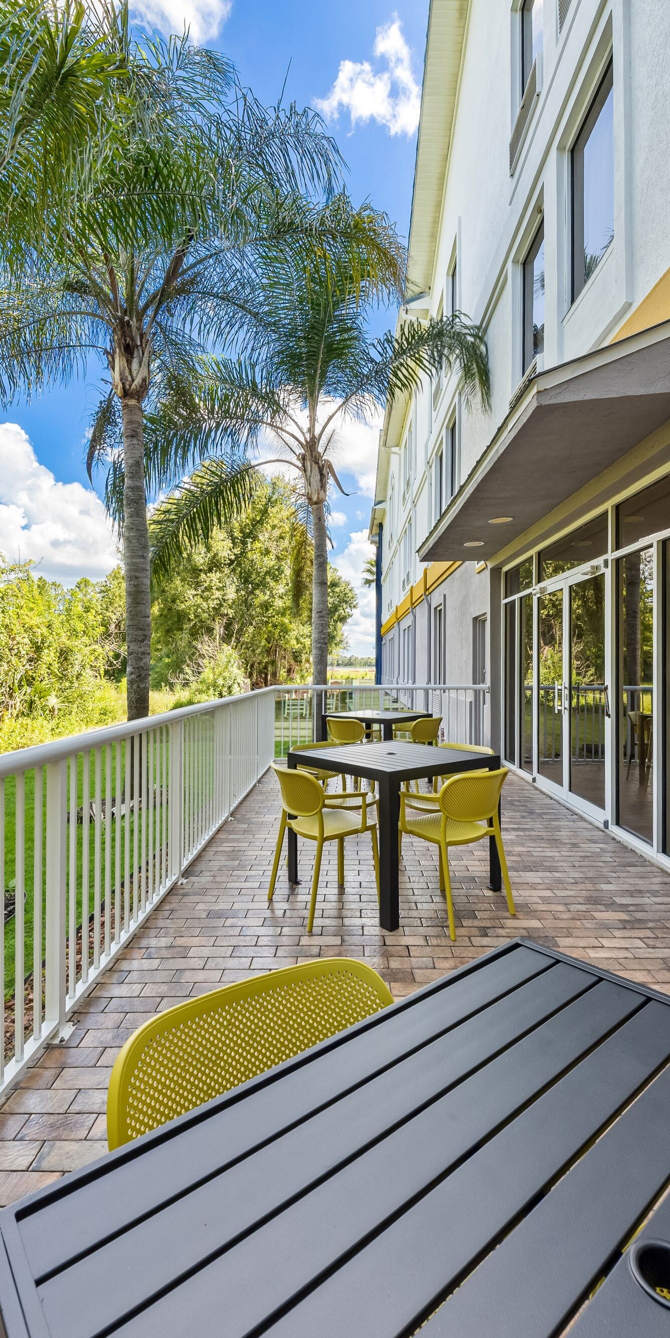 Patio tables overlooking landscaped lawn and palms