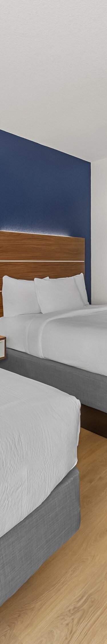 Two queen beds facing wall-mounted TV