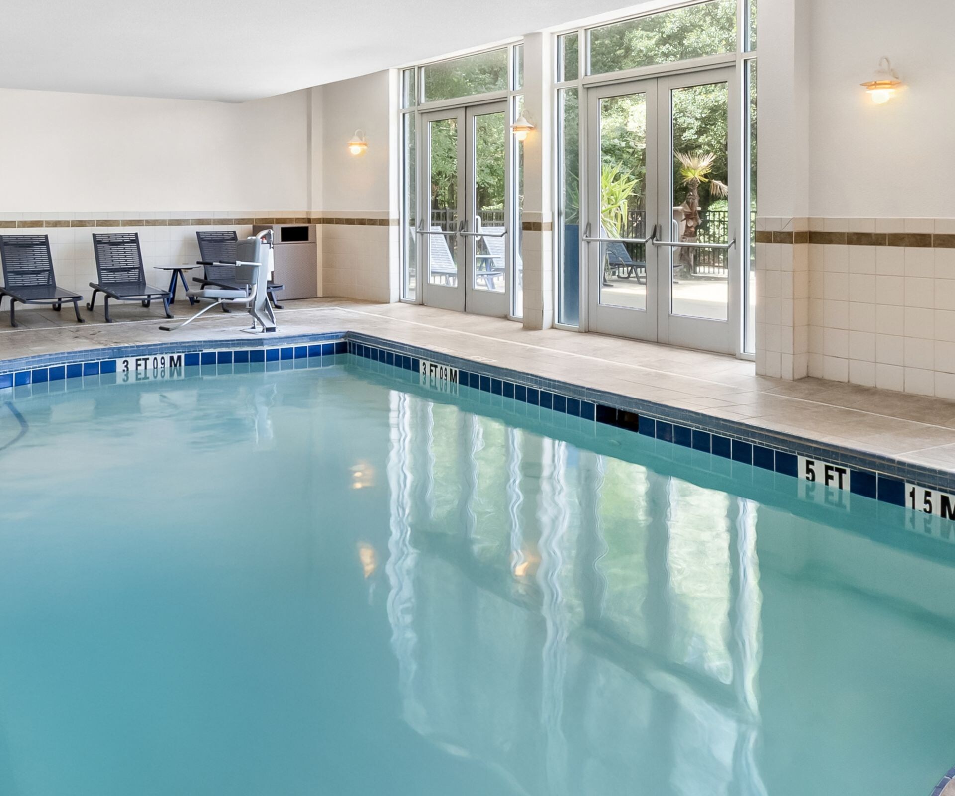 Indoor pool, outdoor patio and deck with chairs.