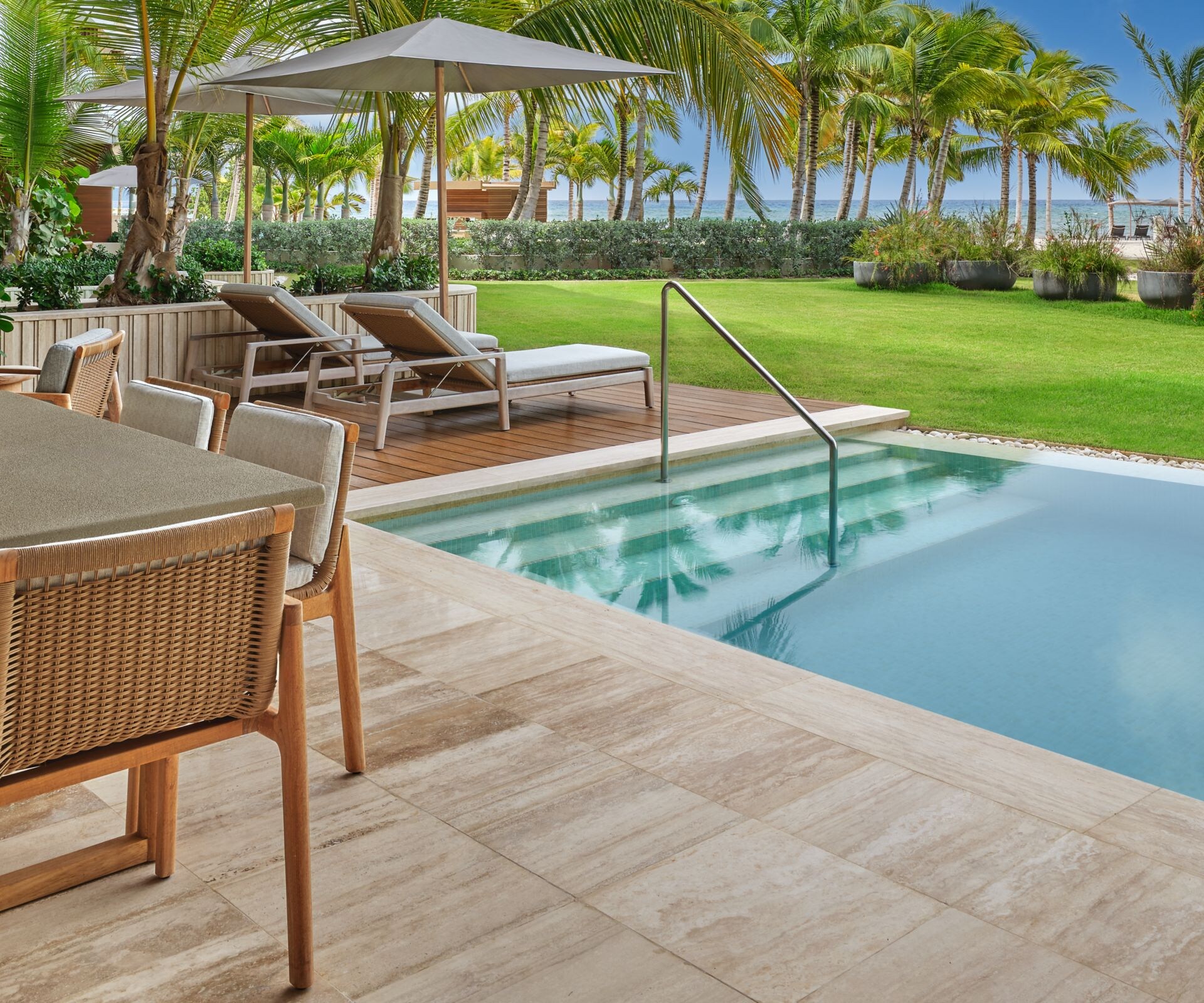 Furnished terrace beside a pool and palm-lined law