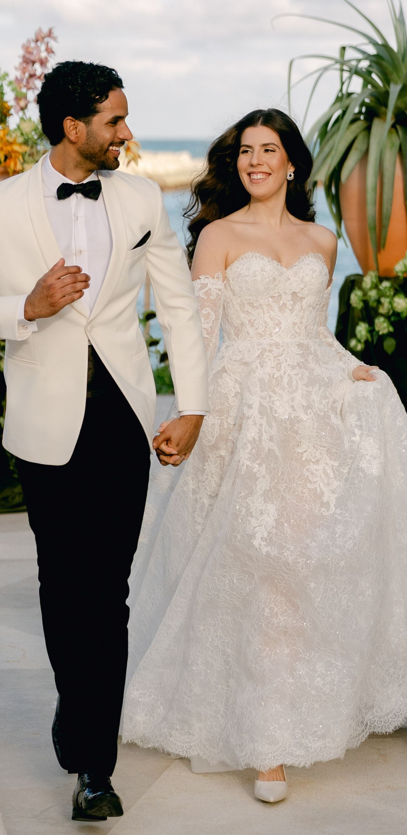 Couple in wedding attire walking at oceanfront