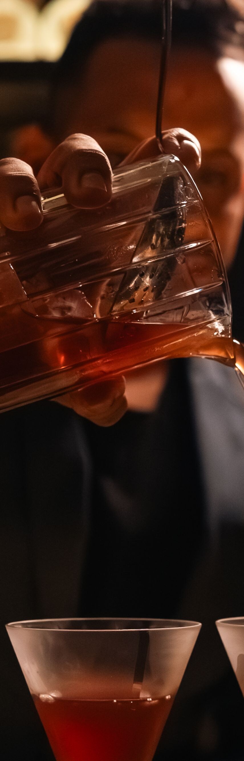 Bartender pouring a cocktail from a glass pitcher