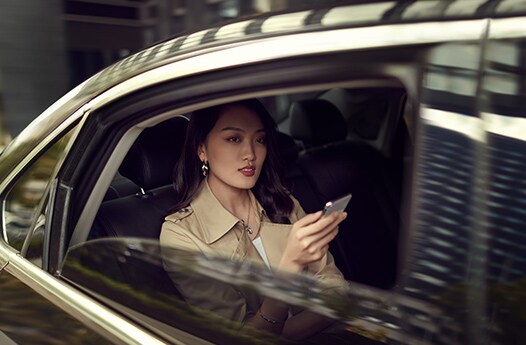 차에서 휴대폰을 보고 있는 여성