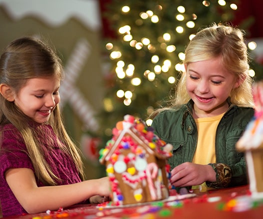 two children decorating a gingerbread house