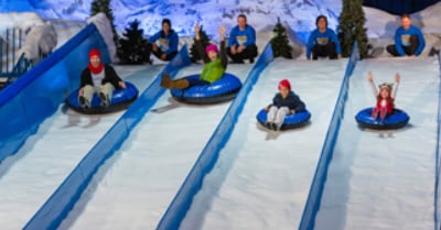 people going down a snowy incline on inflatable tubes