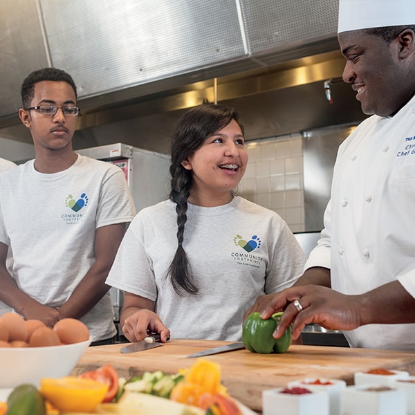 A male and female student talking to a chef