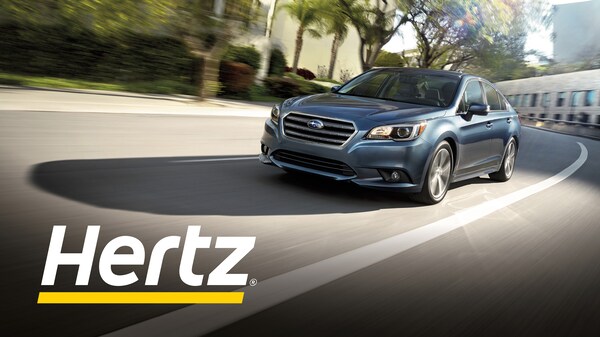 Subaru driving down road with Hertz logo. 