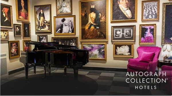 The Raleigh Room with piano, bright purple armchairs, and historic-themed portraits on the walls