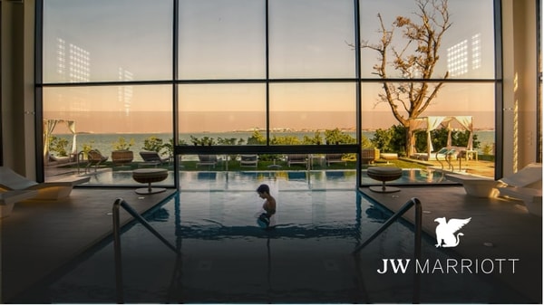 Spa style indoor/outdoor pool with towering window and a man standing in the water