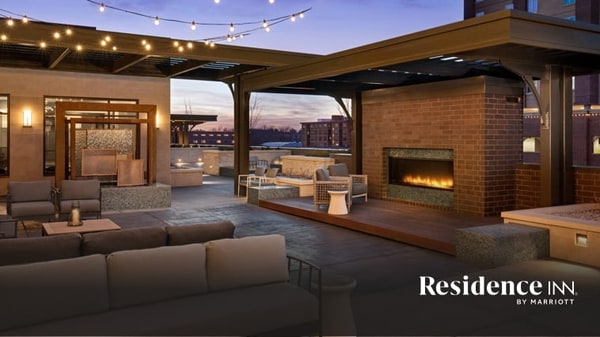 Outdoor lounge at dusk with large fireplace, sofa seating and string lighting