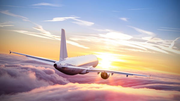 Un avión atravesando las nubes mientras se pone el sol