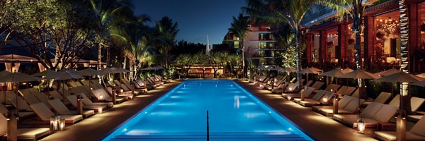 Pool lined with palm trees at night