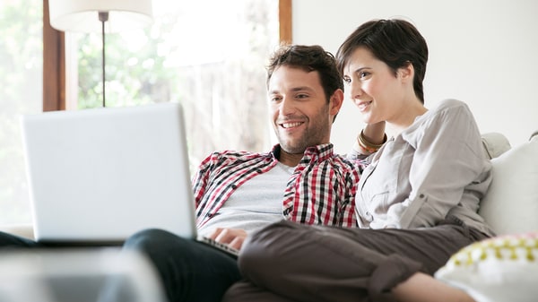 Couple sitting on the sofa with laptop