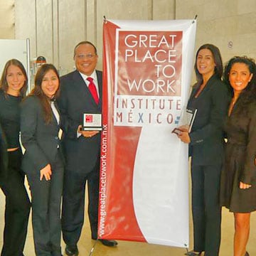 Five associates stand by a “Great Places to Work” banner