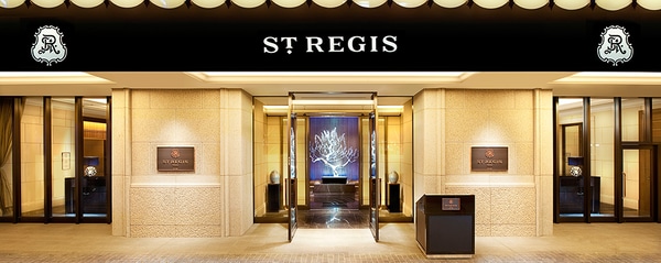 The dramatically lit front entrance to an elegant St. Regis hotel.