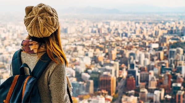 A woman with a backpack looking at the sprawling city below