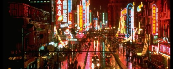 Full view of bright store lights shining at night over Nanjing road in Shanghai.