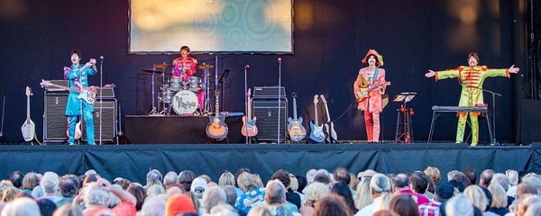 Full view of musicians on stage in neon colorful outfits performing for a crowd in San Diego.