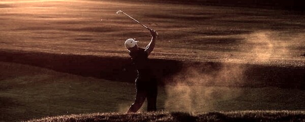 A male golfer takes a swing on a golf course during the sunset in San Diego.