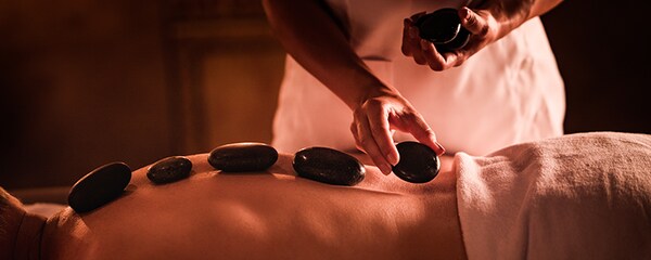 Candle light view of hot stone therapy being massaged into a man's back in Palm Desert.
