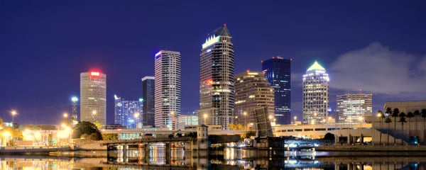 The Tampa skyline lit up at night over the water.