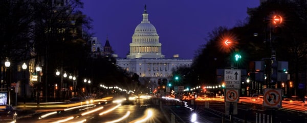 Car headlights streak in the night as they drive through Washington, DC past the US Capitol