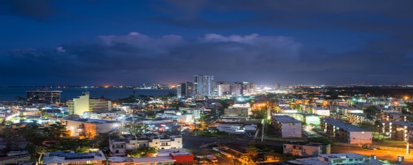 San Juan, Puerto Rico glows at night as gentle clouds sit overhead above the water