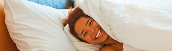 Woman smiling under bed covers