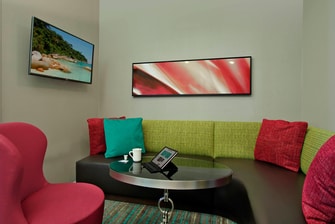 semi-private seating in lobby with tv and decorative cushy pillows, couch, chair, and round table