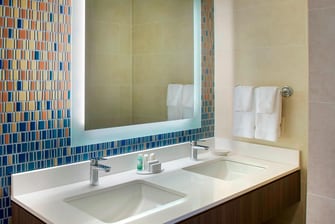 Waschtisch im Bad eines Gästezimmers mit zwei Doppelbetten